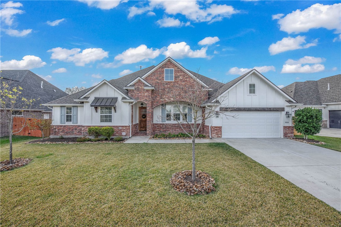 View of front of home with a front yard and a gara