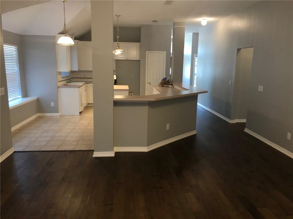 a view of a kitchen with kitchen island a sink wooden floor and a large window