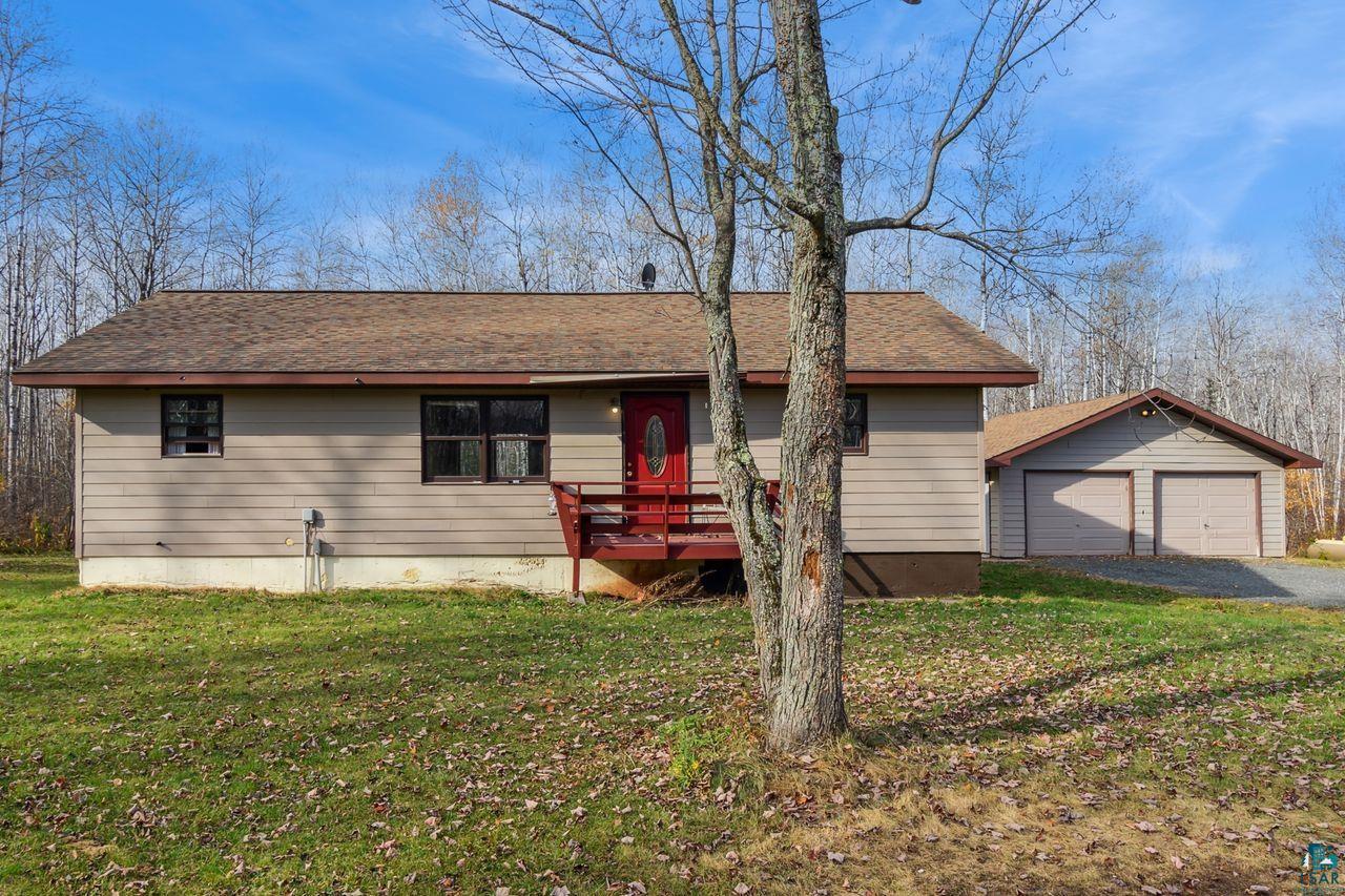 View of front of property featuring a wooden deck, a front yard, an outbuilding, and a garage