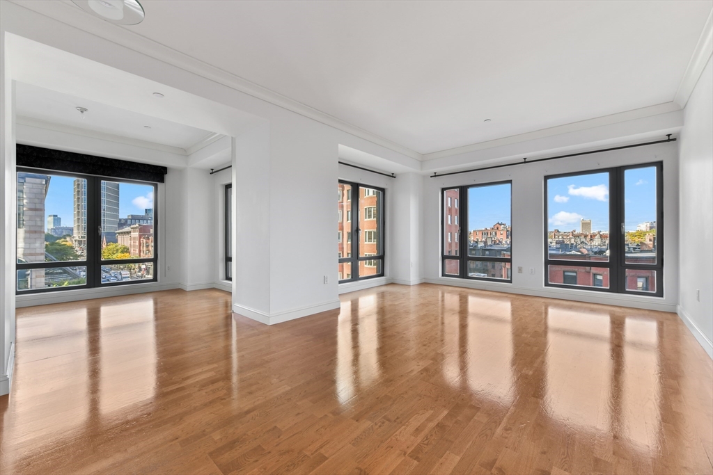 a view of an empty room with window and wooden floor