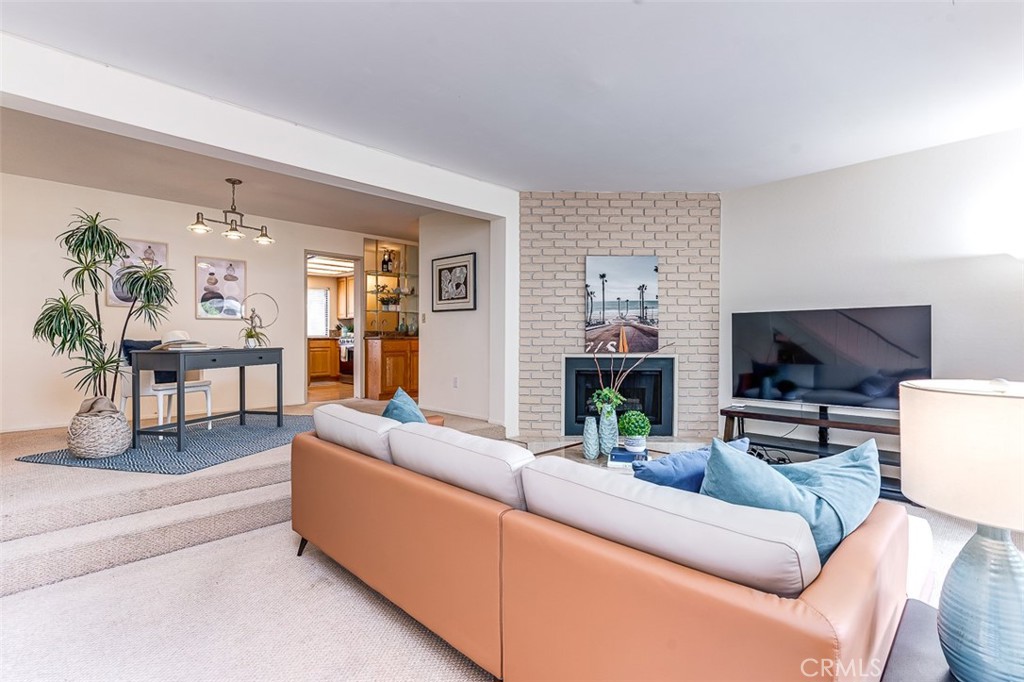 a living room with furniture a fireplace a flat screen tv and a large window