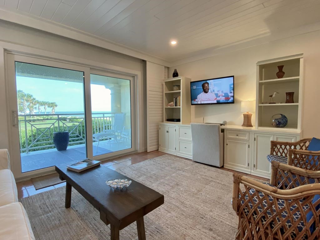 a living room with furniture a flat screen tv and a floor to ceiling window