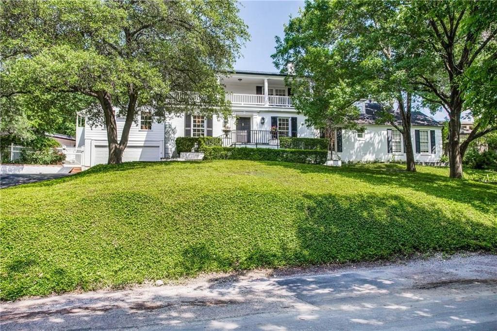 a view of a house with a big yard and large trees