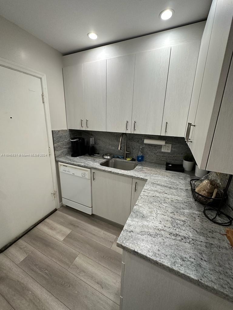 a kitchen with granite countertop white cabinets and sink