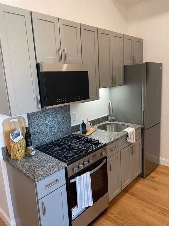 a kitchen with granite countertop a sink stove and refrigerator