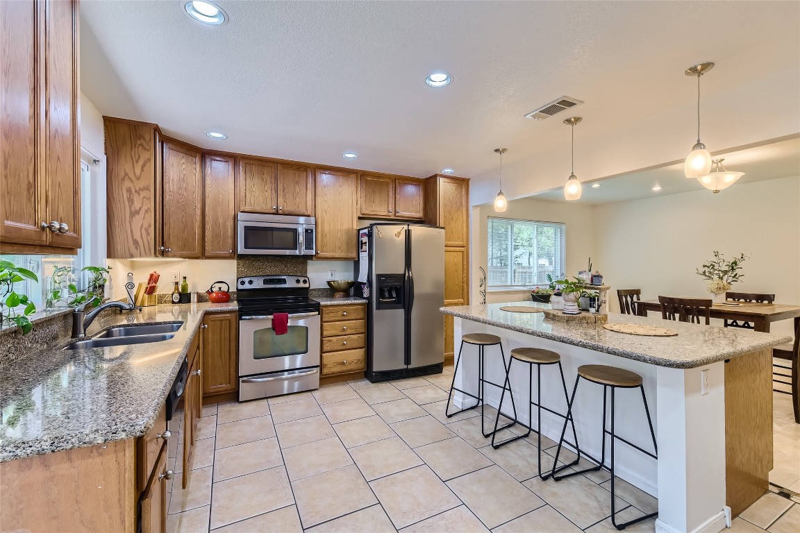 a kitchen with stainless steel appliances granite countertop a sink stove refrigerator and cabinets