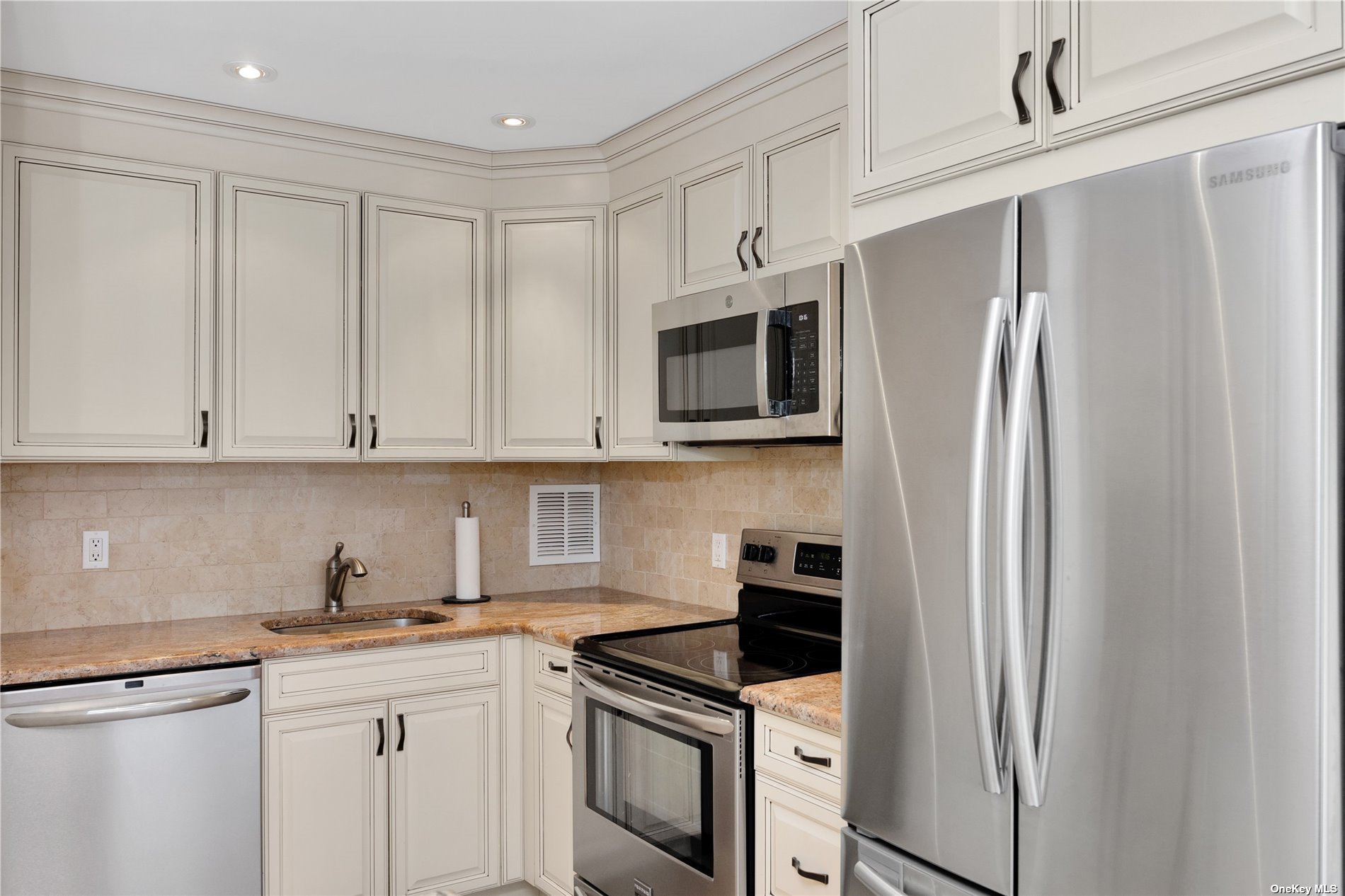 a kitchen with stainless steel appliances granite countertop a refrigerator sink and white cabinets