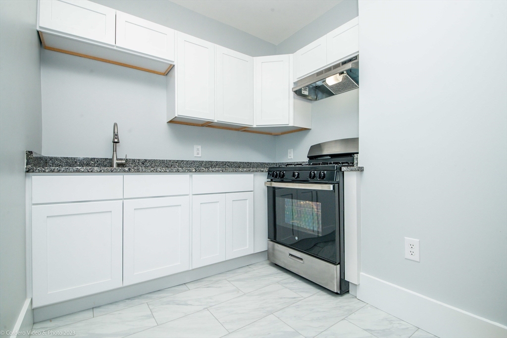 a kitchen with granite countertop white cabinets and white appliances