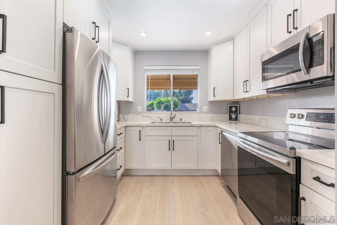 a kitchen with white cabinets stainless steel appliances and a window