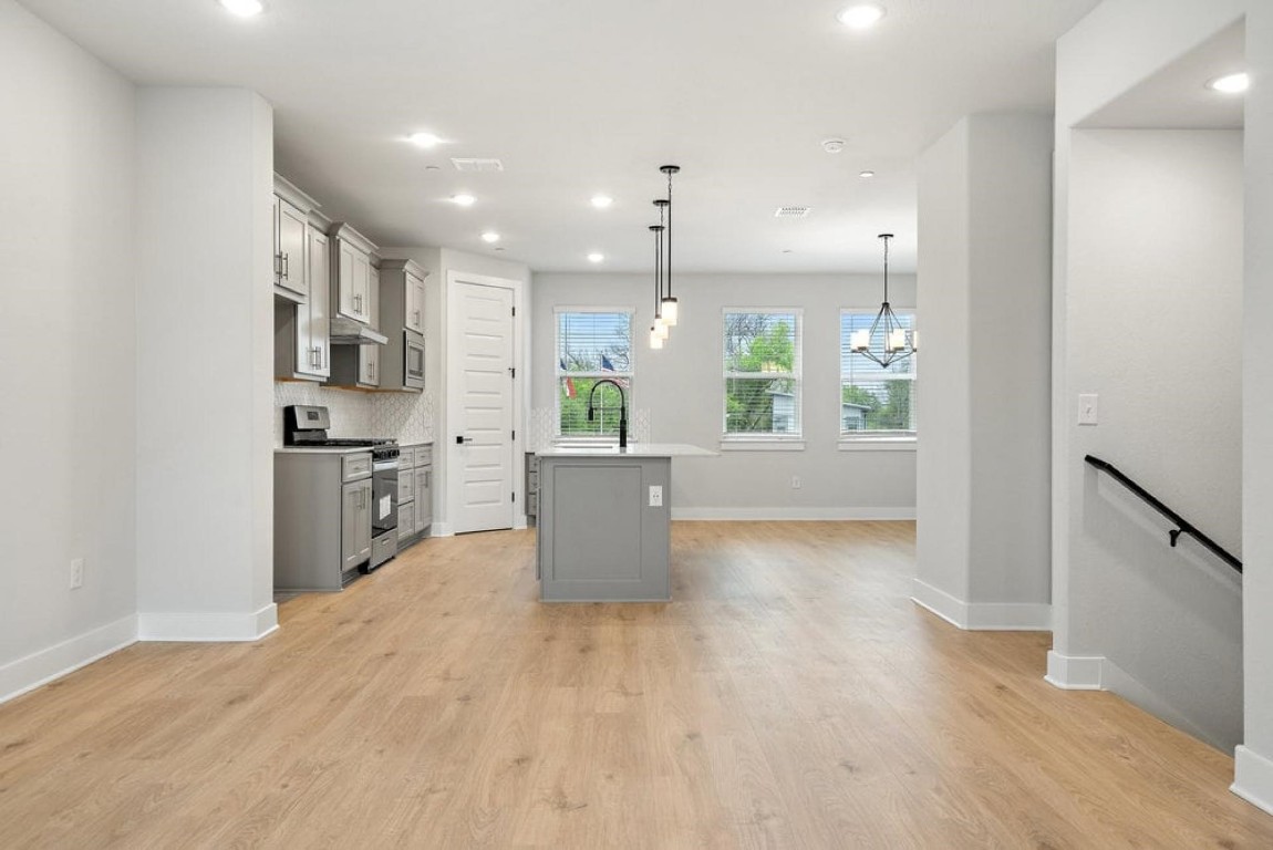 a open kitchen with stainless steel appliances granite countertop a refrigerator a sink dishwasher a stove and white countertops with wooden floor