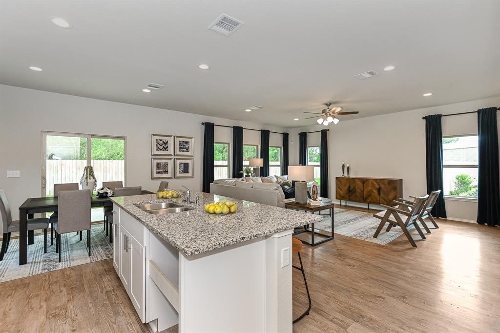 a open dining room with stainless steel appliances granite countertop a couch and a dining table with wooden floor