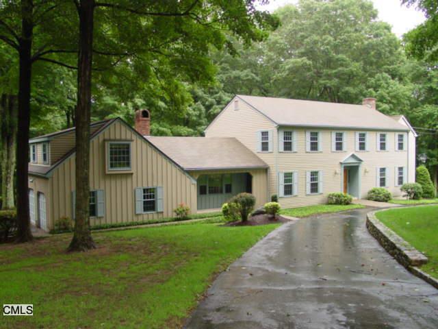 a view of a white house with a big yard plants and large trees