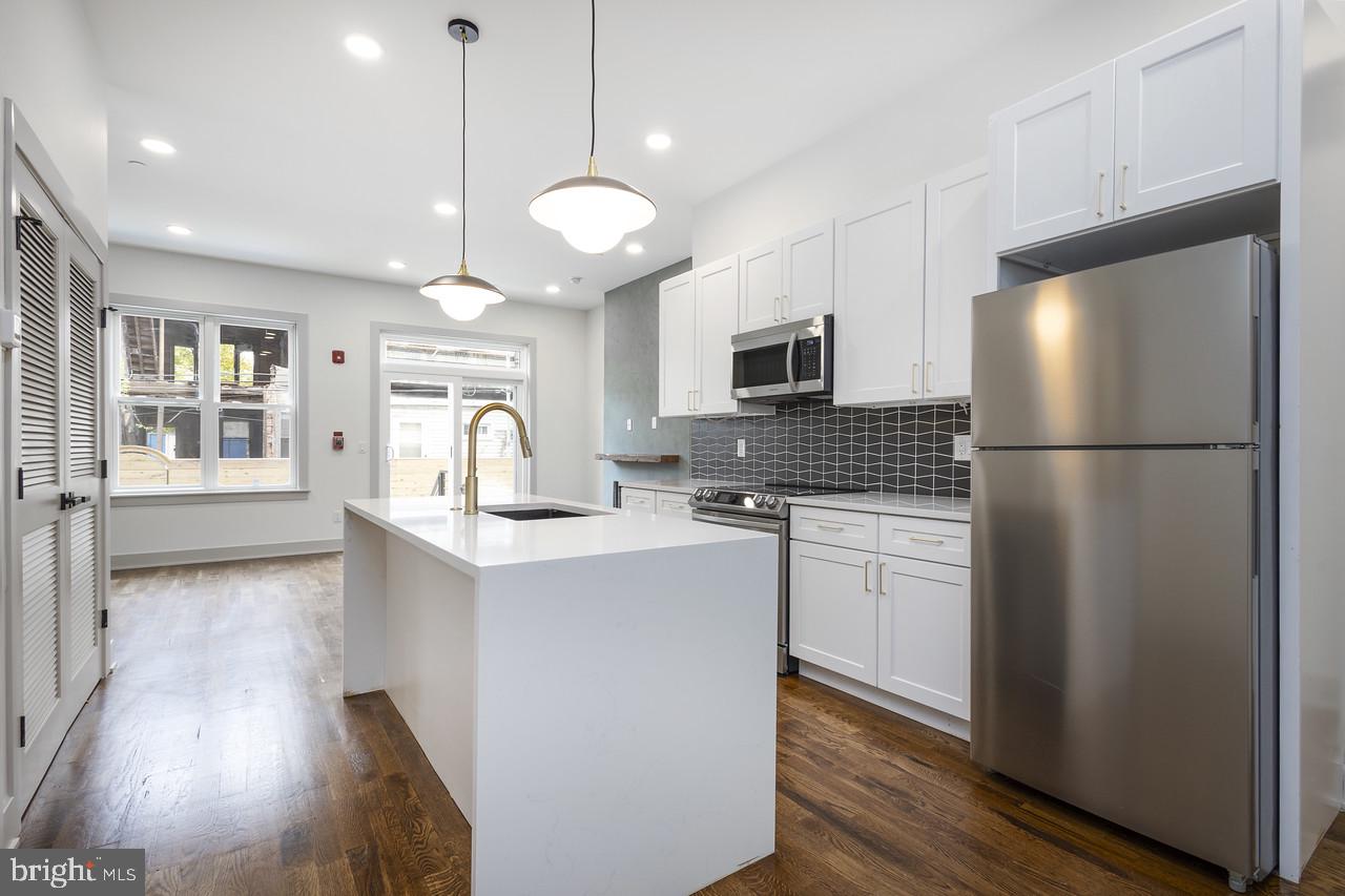 a kitchen with a refrigerator a stove top oven a sink and cabinets