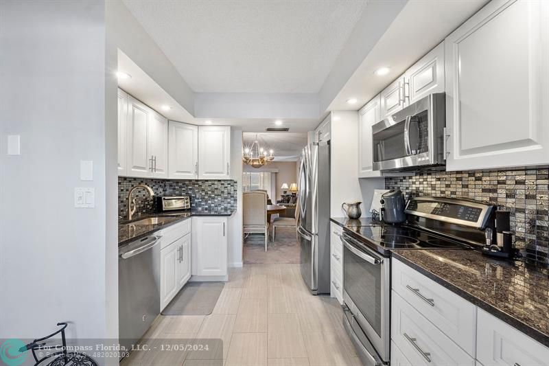 a kitchen with stainless steel appliances granite countertop a stove refrigerator and cabinets