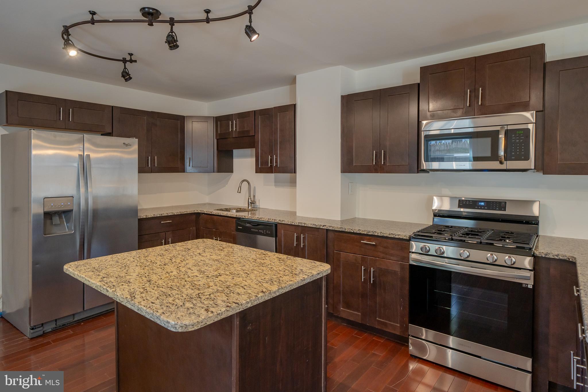 a kitchen with kitchen island a counter space a sink stainless steel appliances and cabinets