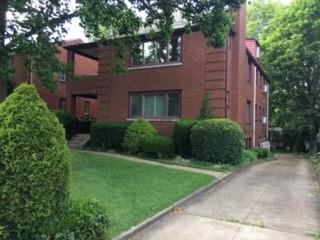 a view of a brick house with a yard and large trees