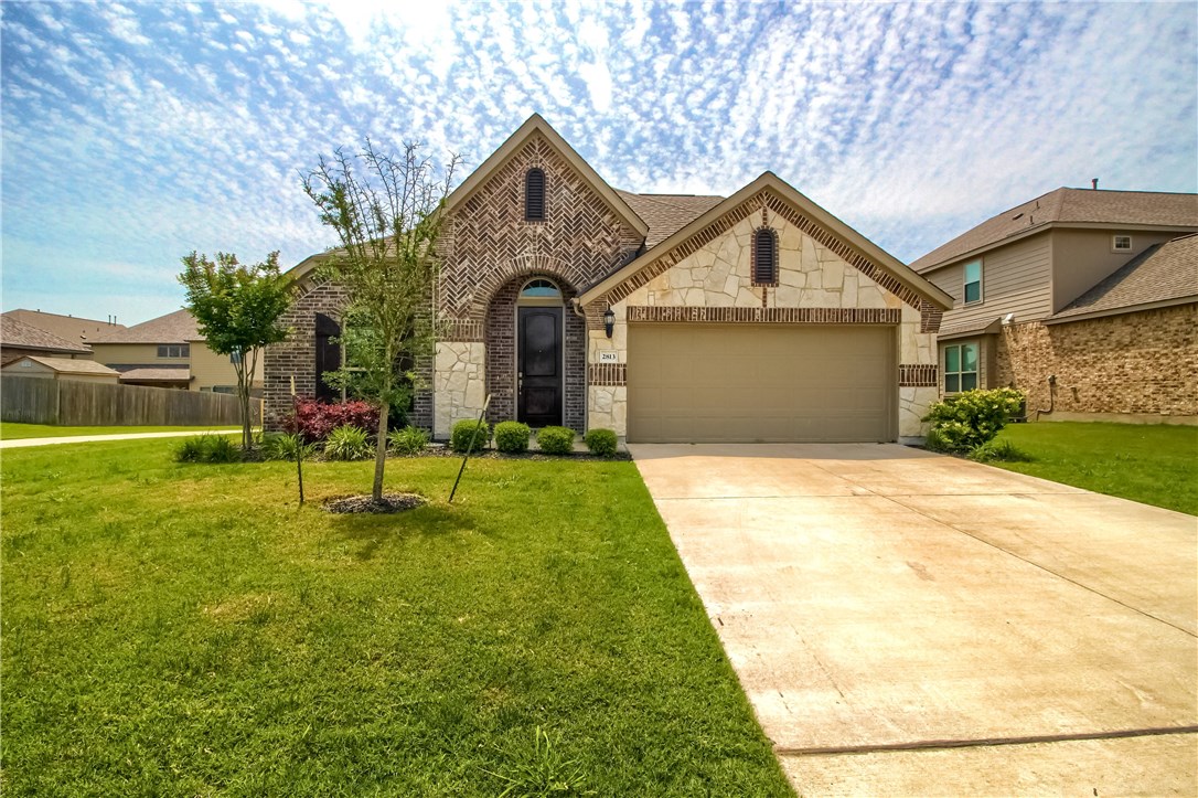 a front view of a house with a yard and trees