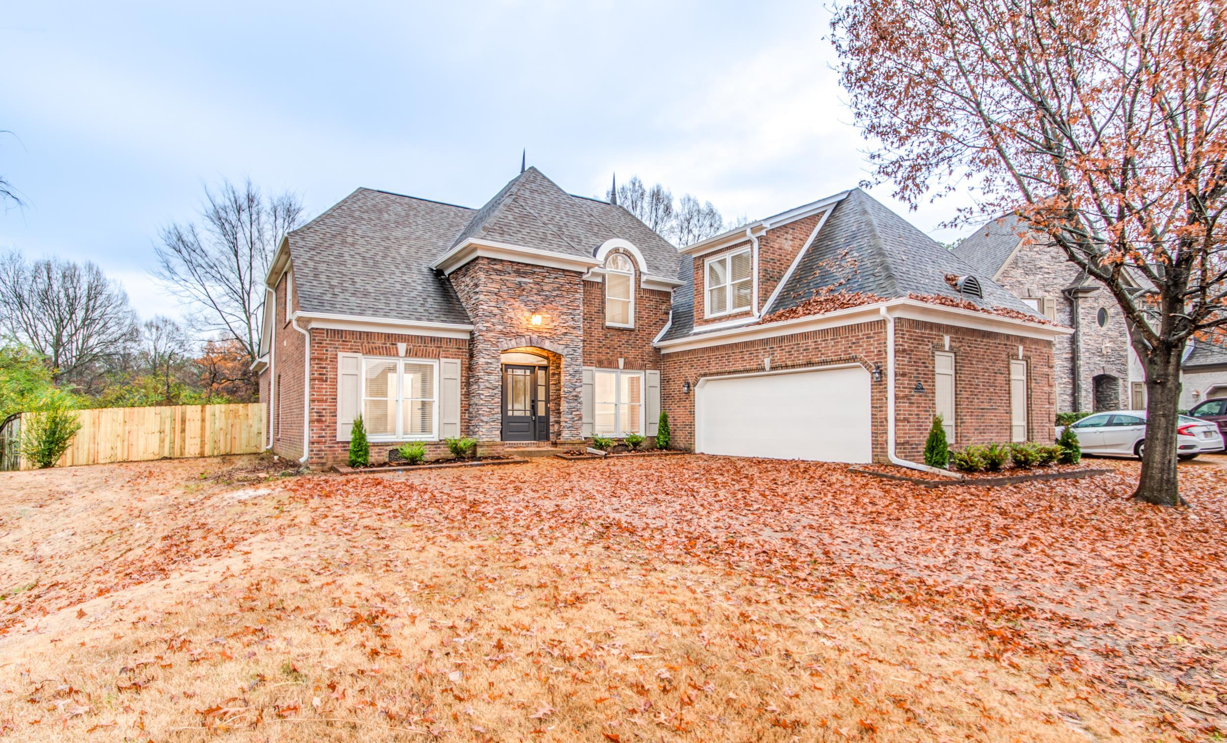 a front view of a house with a dirt yard and a large tree