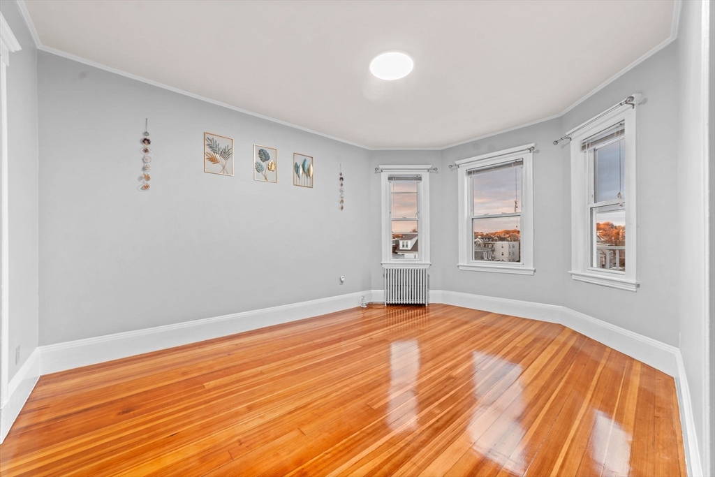 a view of an empty room with window and wooden floor