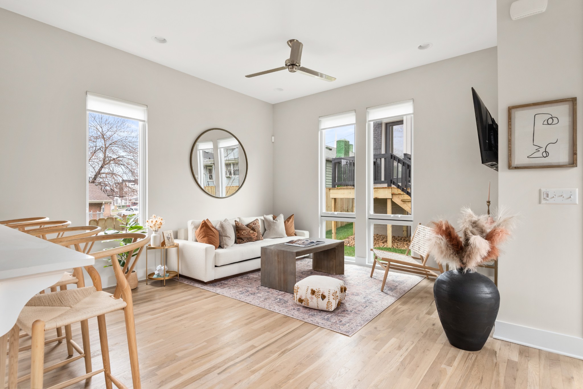 a living room with furniture a clock potted plants and wooden floor