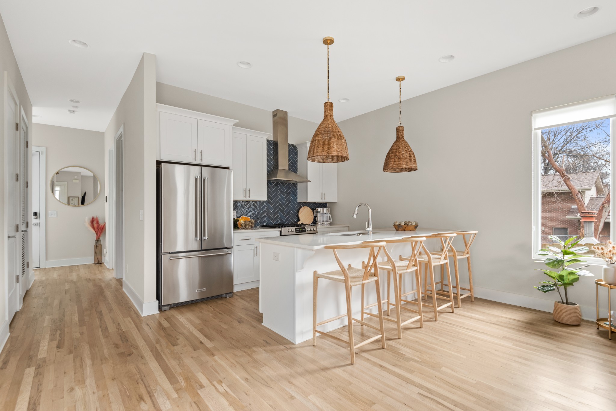 a kitchen with stainless steel appliances granite countertop a refrigerator a sink dishwasher a stove a dining table and chairs with wooden floor