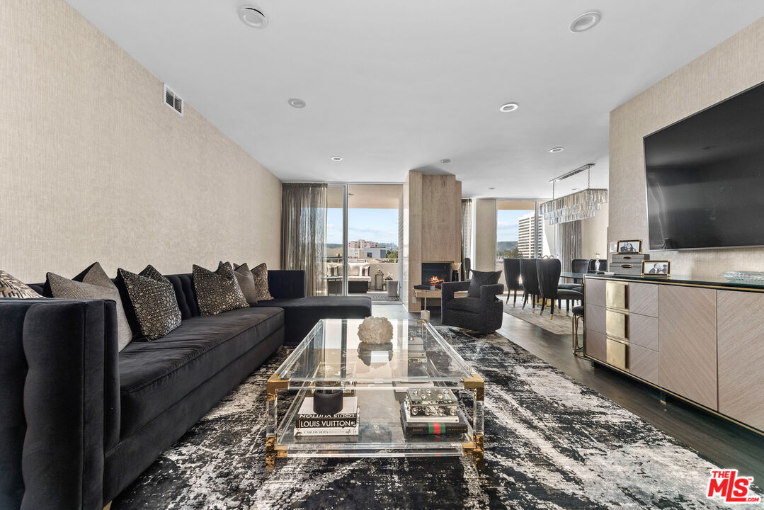 a living room with furniture a flat screen tv and kitchen view