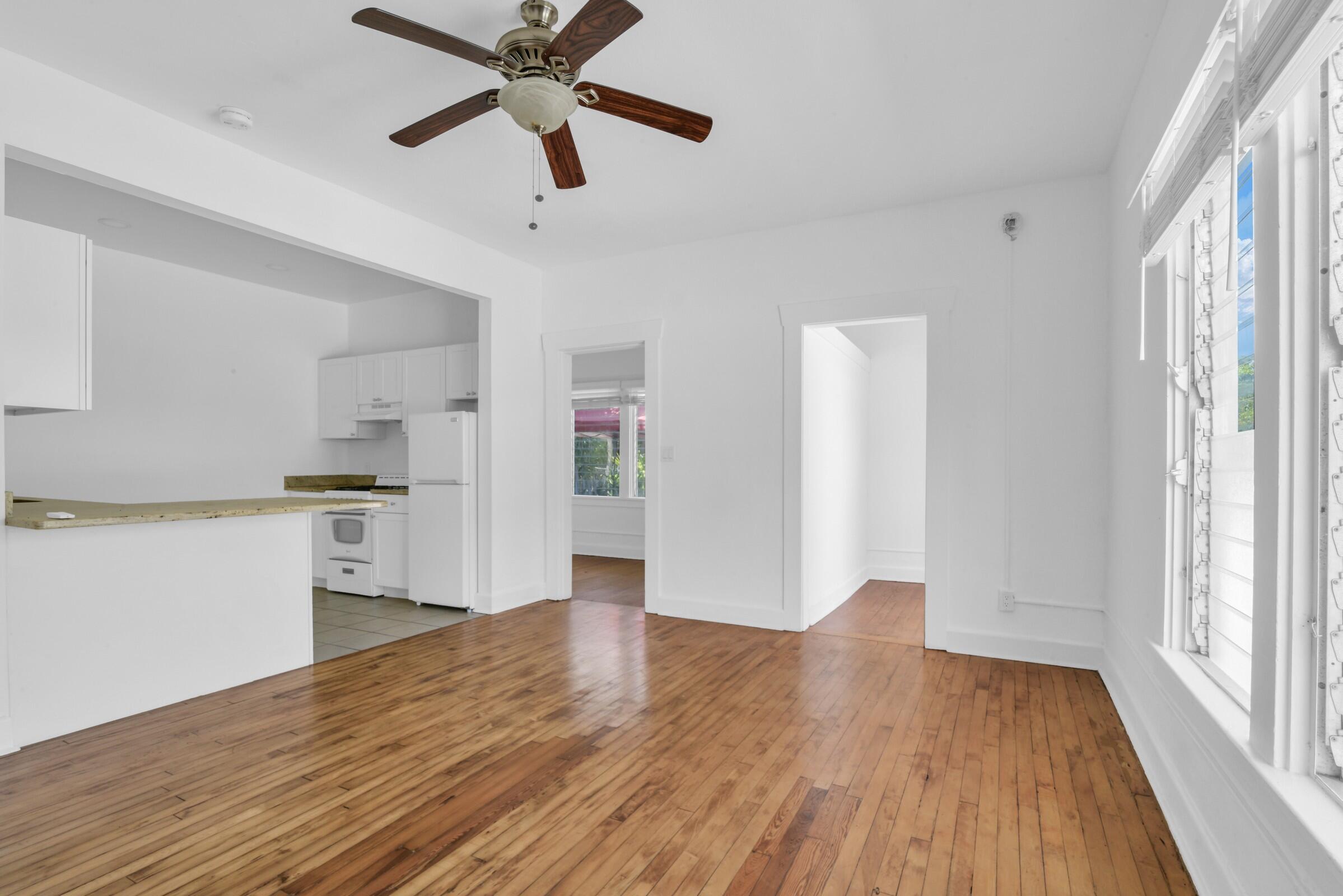 a view of a kitchen with wooden floor a ceiling fan and windows