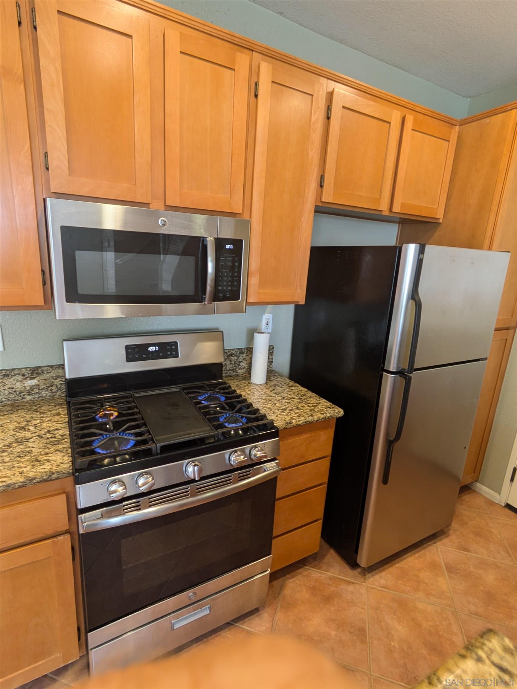 a kitchen with granite countertop a refrigerator stove and microwave