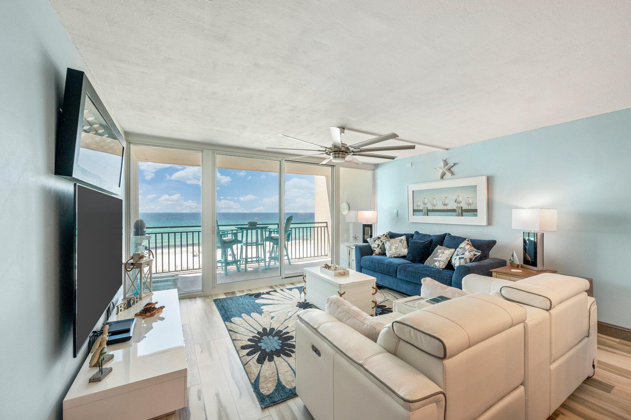 a living room with furniture a flat screen tv and a floor to ceiling window