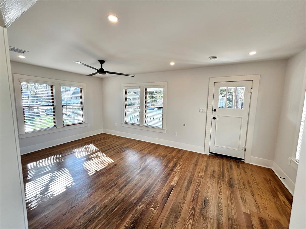 a view of empty room with wooden floor and fan