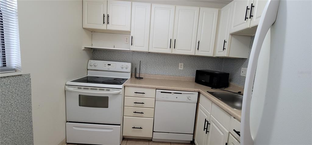 a kitchen with white cabinets and white appliances