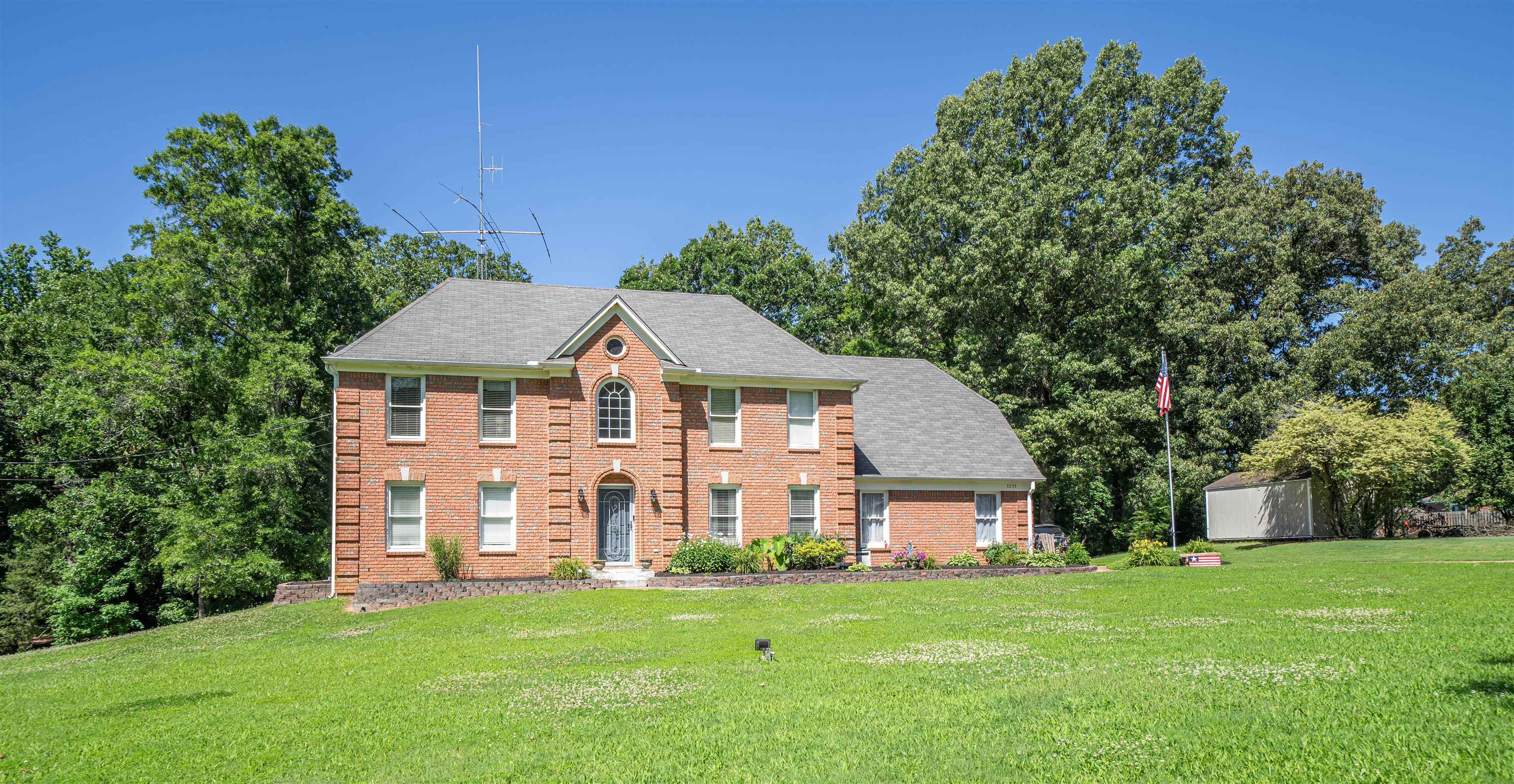 a view of a big house with a big yard and large trees