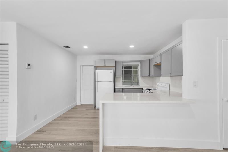 a large white kitchen with kitchen island a sink a stove and a refrigerator