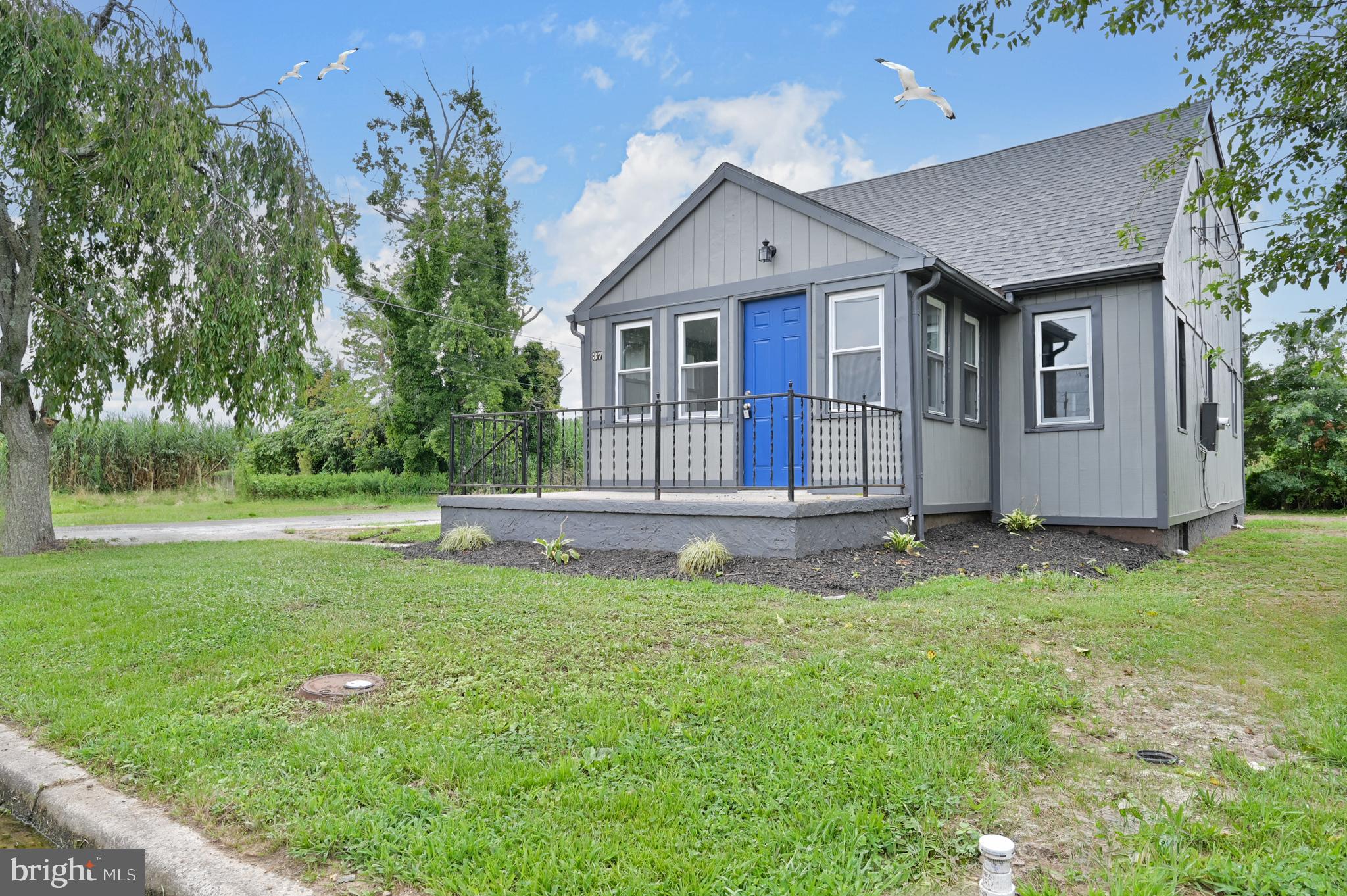 a house that is sitting in the grass with tress in the background