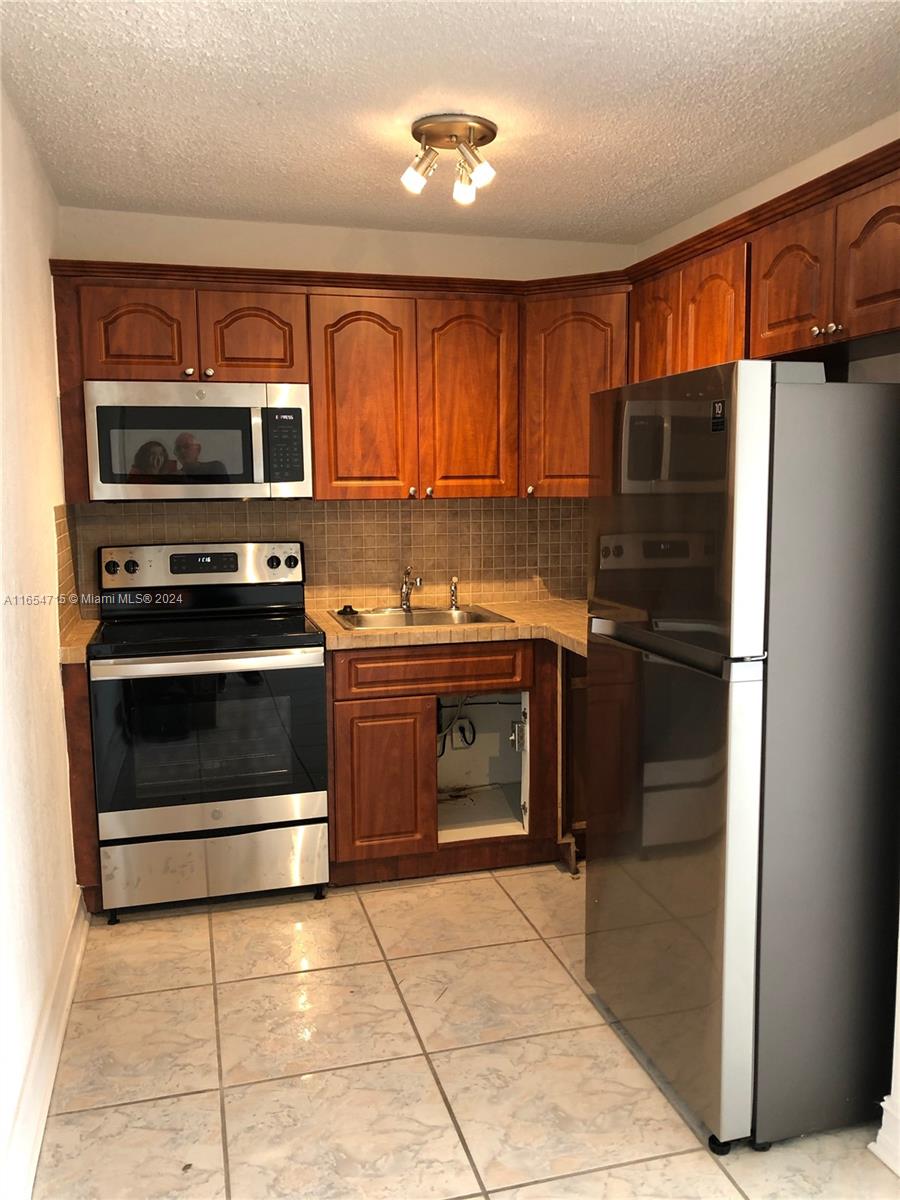 a kitchen with granite countertop a stove top oven and refrigerator