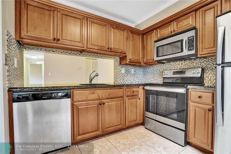 a kitchen with stainless steel appliances granite countertop a stove microwave and cabinets