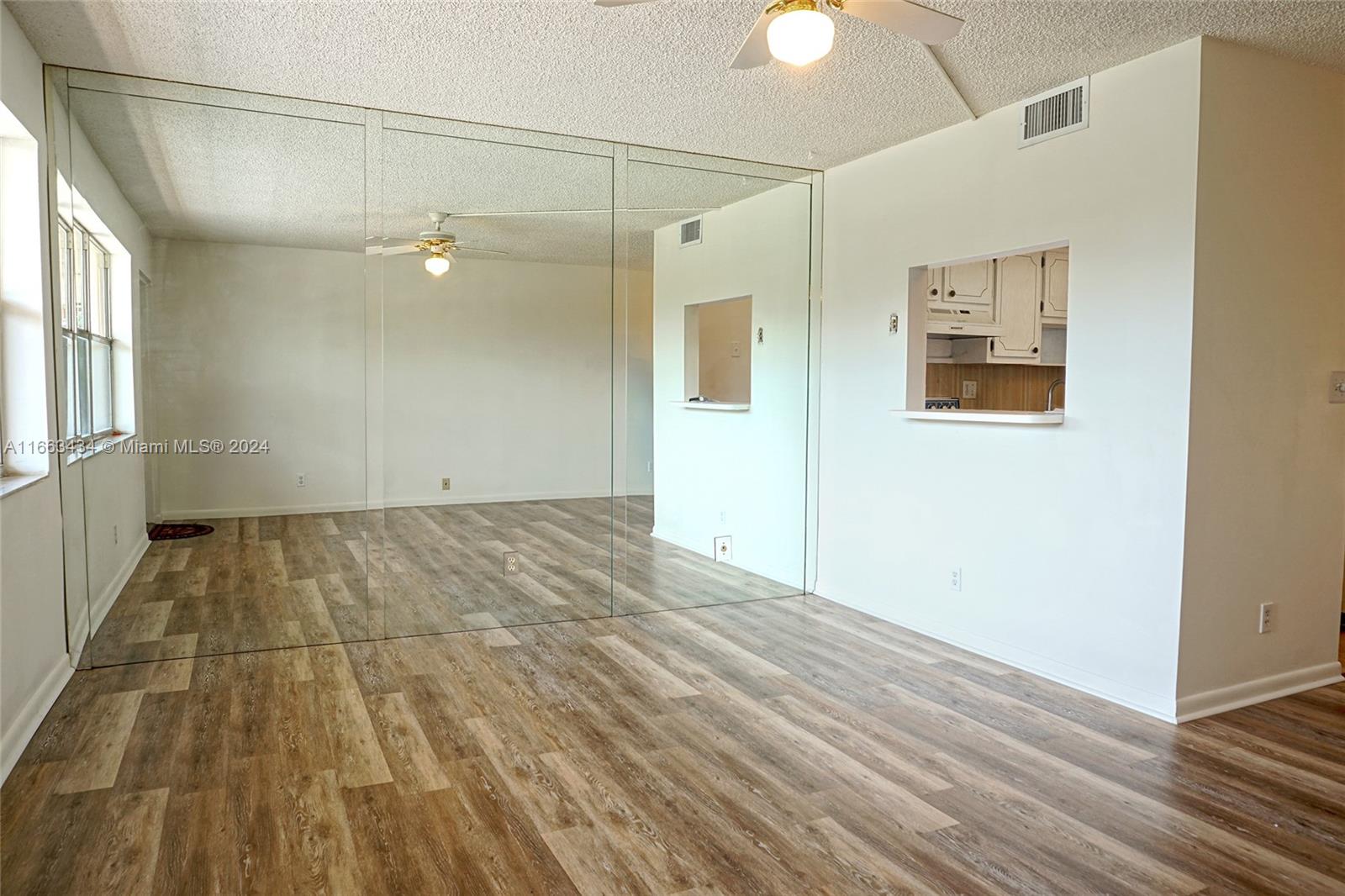 an empty room with wooden floor fan and windows