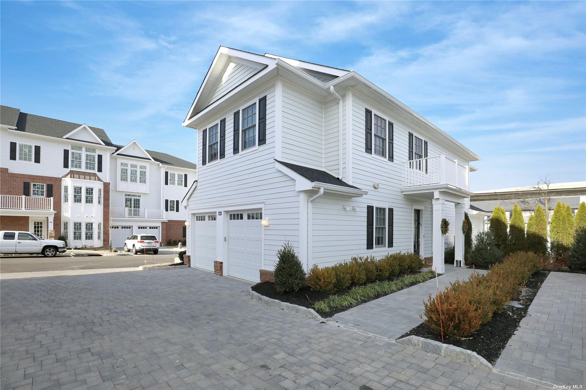 a view of a white house next to a road and yard