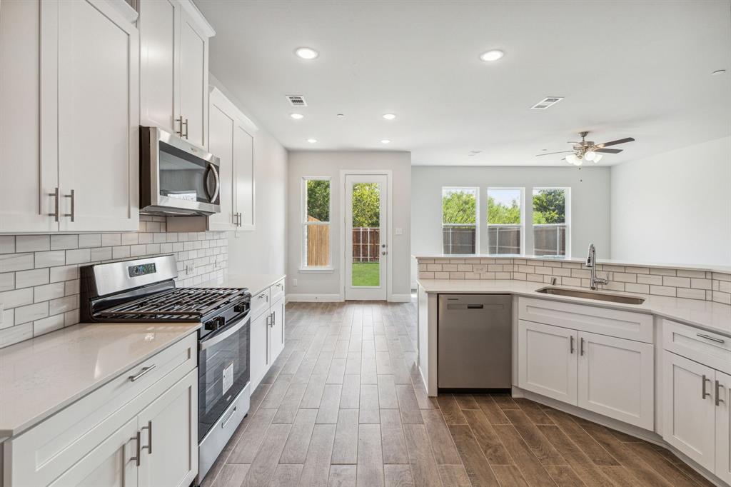 a kitchen with stainless steel appliances kitchen island granite countertop a stove sink and cabinets