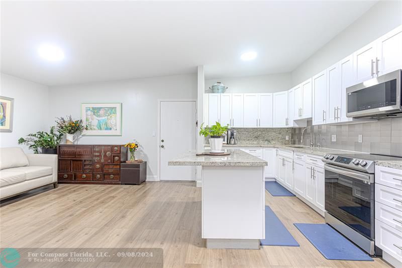 a kitchen with granite countertop a stove a sink and a white cabinets