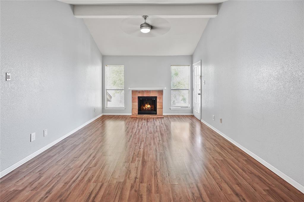 an empty room with wooden floor fireplace and windows