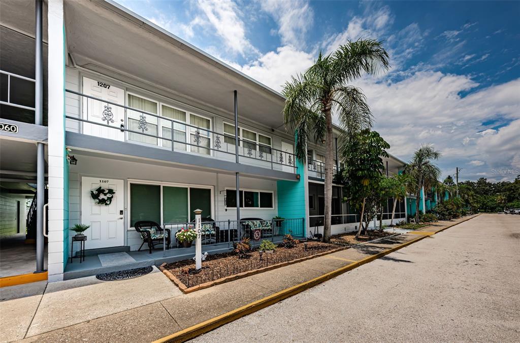 a view of a building with sitting area and palm trees