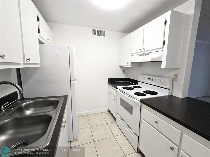 a kitchen with granite countertop a sink stove and white cabinets