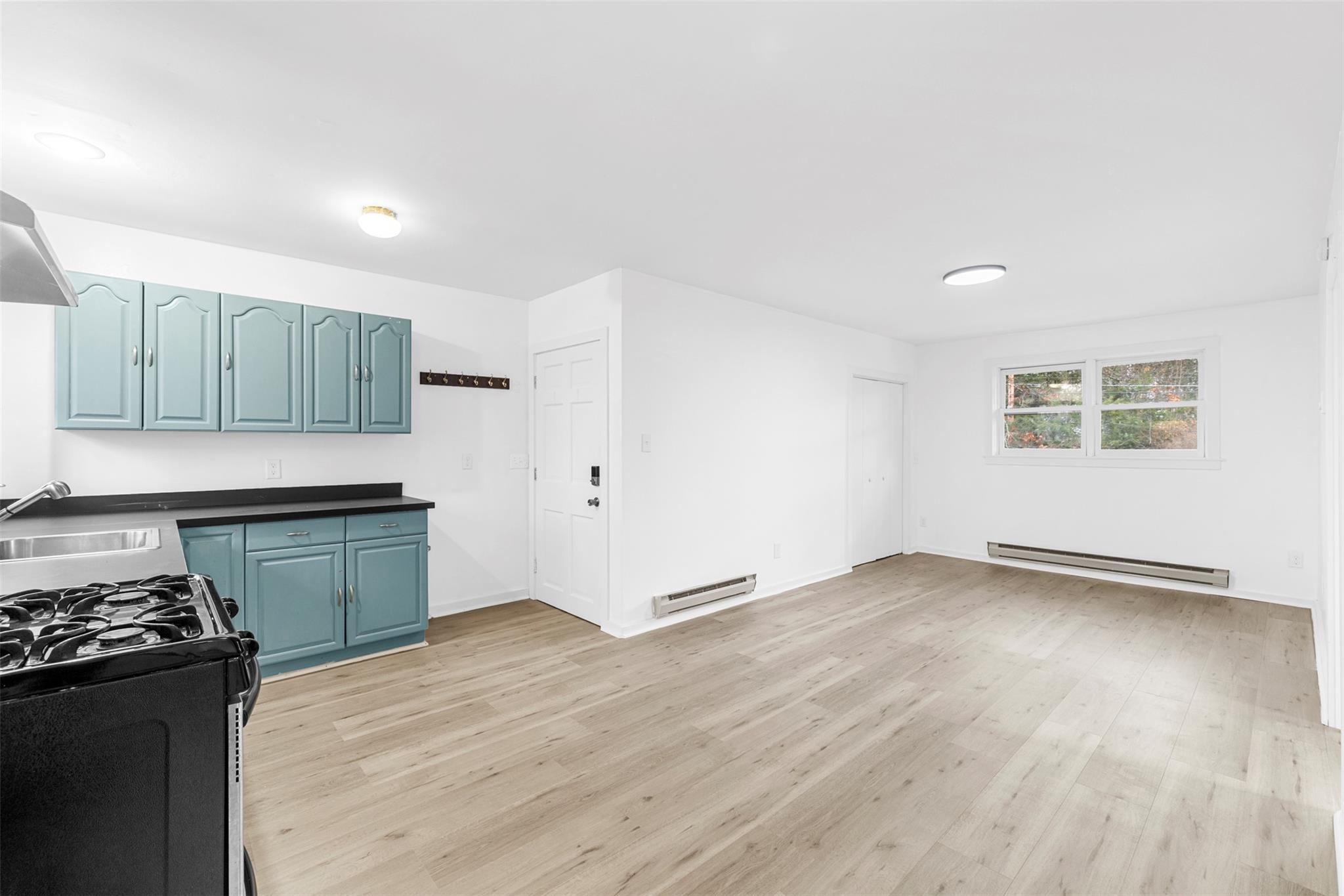 Kitchen with light hardwood / wood-style floors, sink, range, and baseboard heating