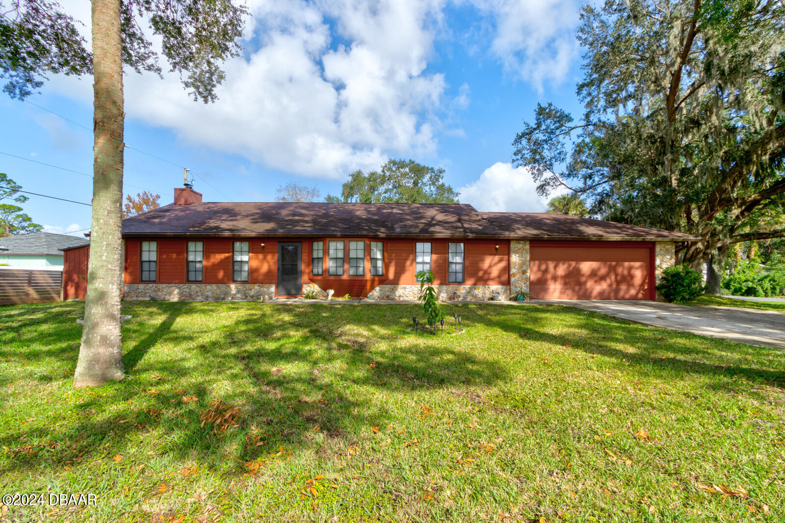 a view of a brick house with a big yard next to a large tree