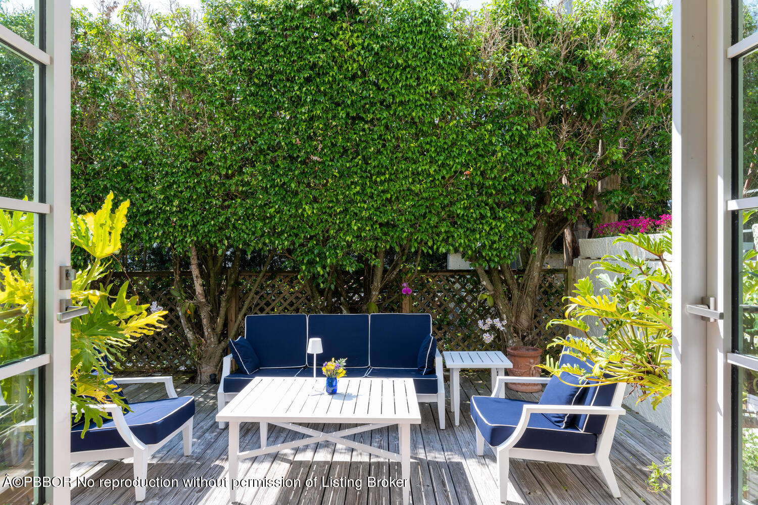 a view of a patio with table and chairs potted plants and floor to ceiling window