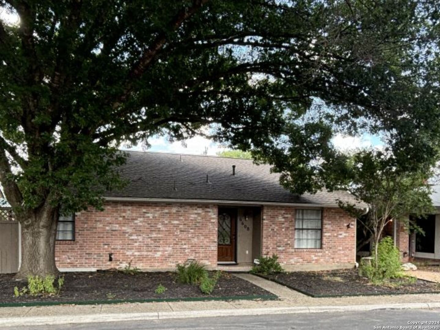 a front view of a house with a tree