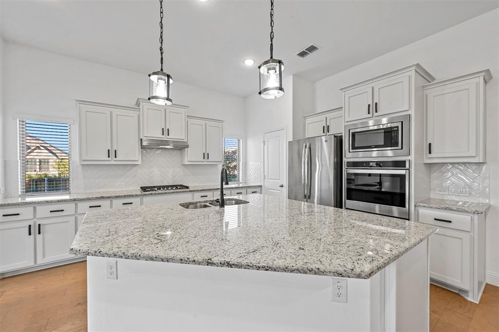 a kitchen with kitchen island granite countertop a sink and refrigerator