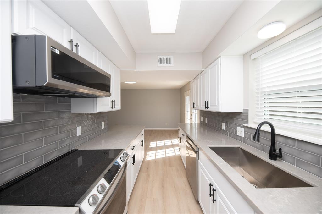 a kitchen with a sink a microwave and cabinets