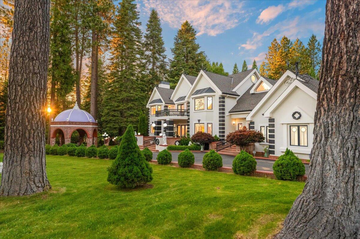 a front view of a house with a garden and trees